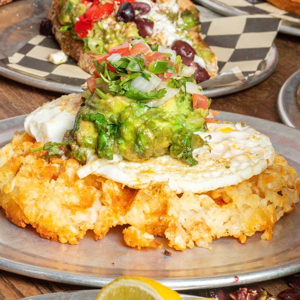 Hash brown waffle topped with a fried egg, guacamole, and pico de gallo.