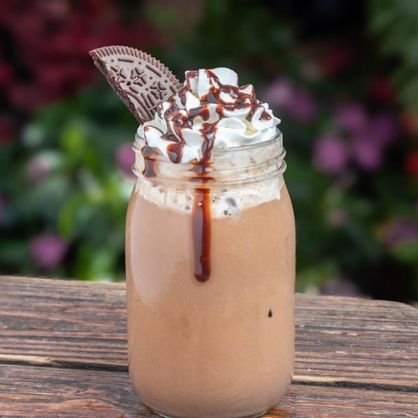 Chocolate milkshake in a mason jar, topped with whipped cream, chocolate drizzle, and a cookie.